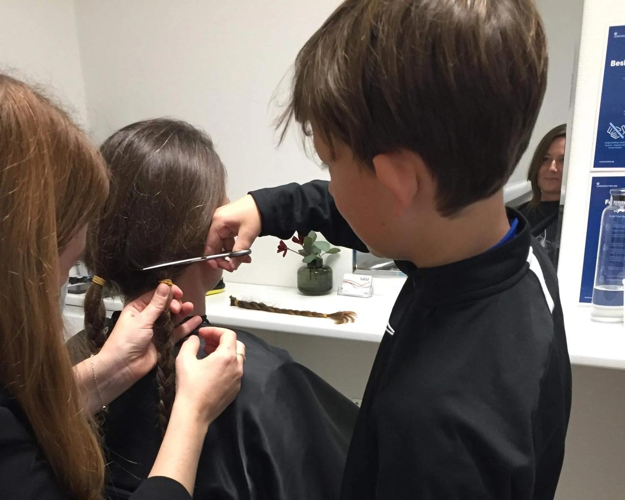 kvinde får  klippe hår af hos frisør