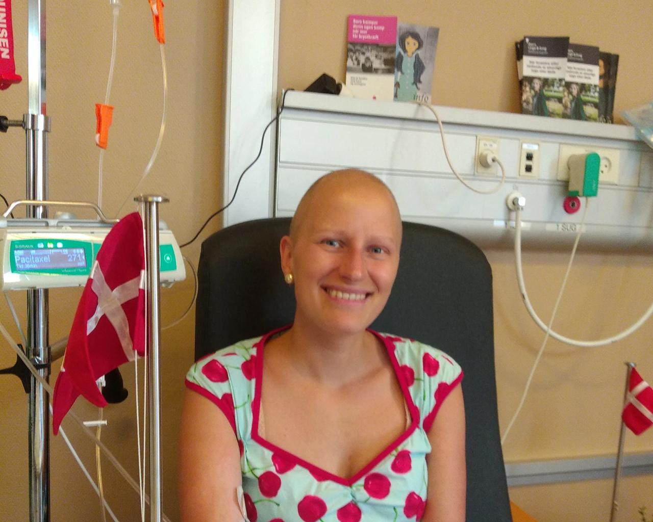 Lisa sidder i lænestol på behandlingsstue, og der er et flag på bordet ved siden af hende. Foto: Privat