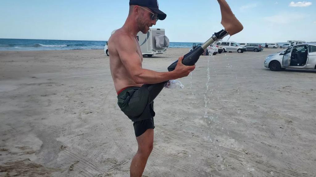 Ung mand står på stranden iført sin benprotese