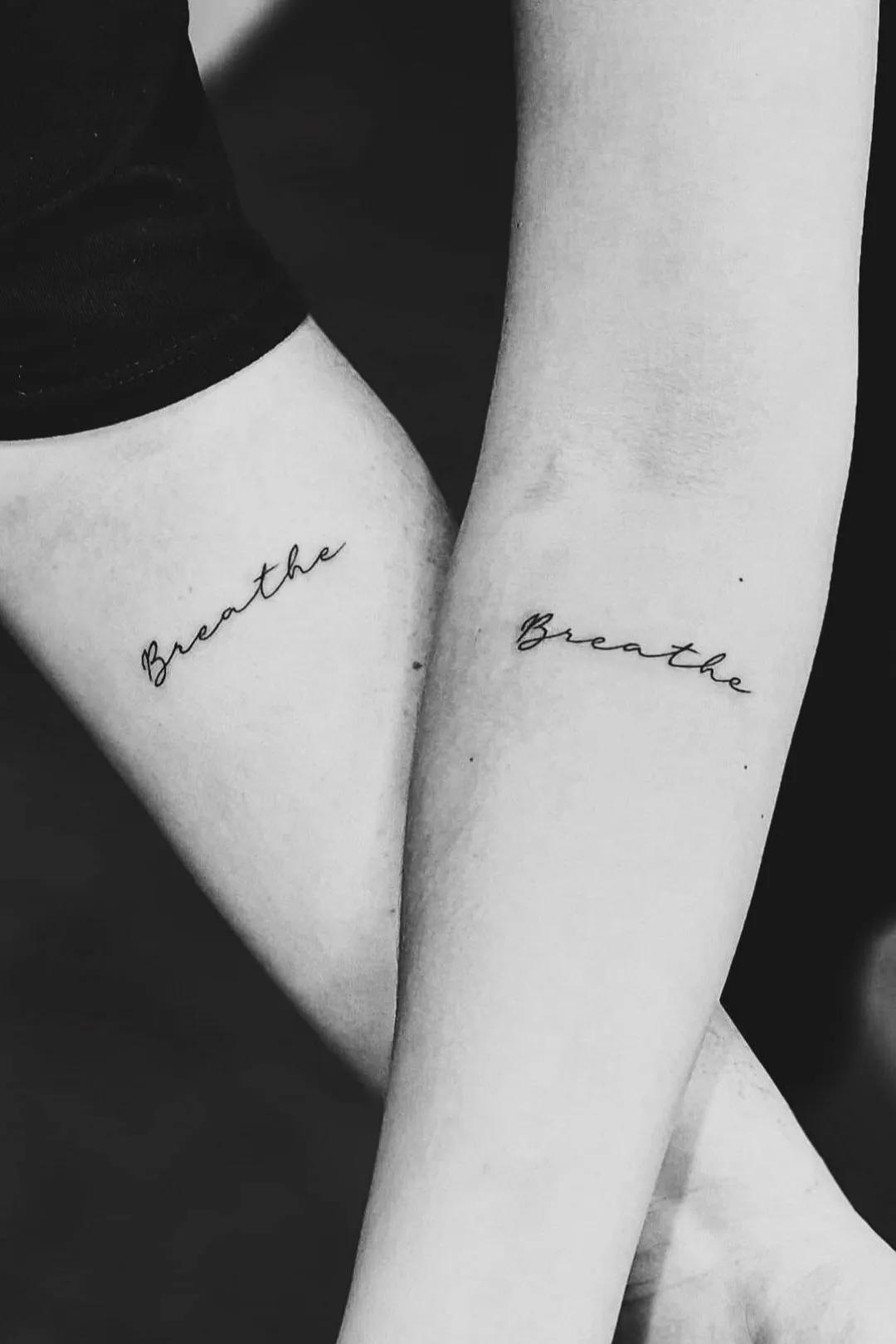 Julie og hendes veninde fremviser deres arme med teksten "breathe" tatoveret. 