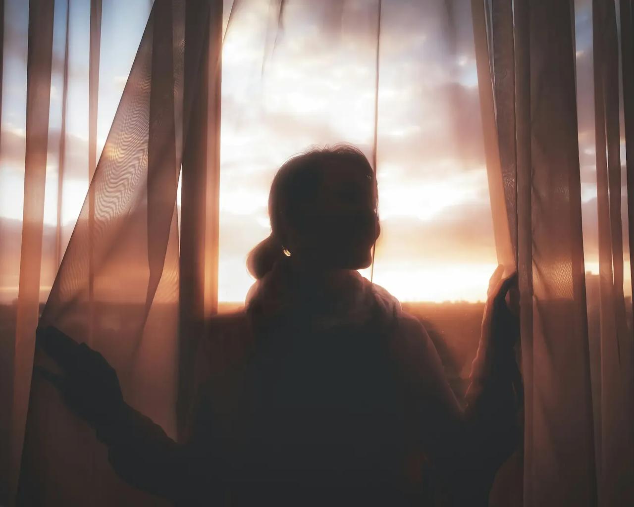 Kvinde står ved et vindue og kigger ud