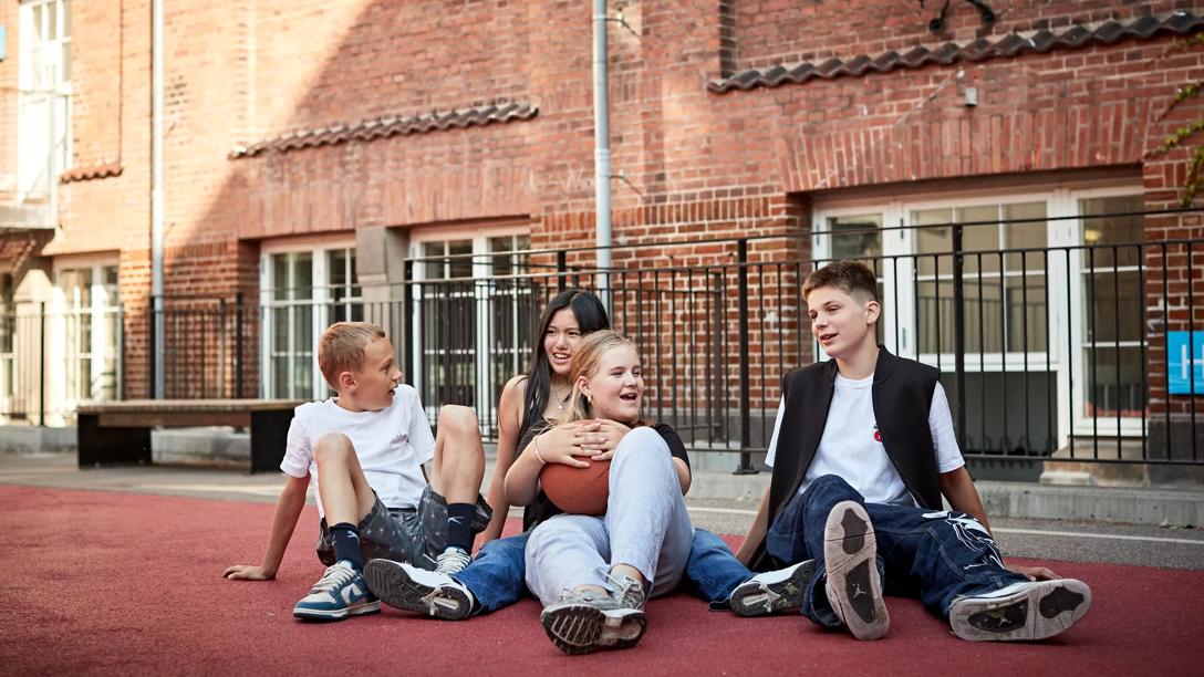 Børn sidder sammen med en bold