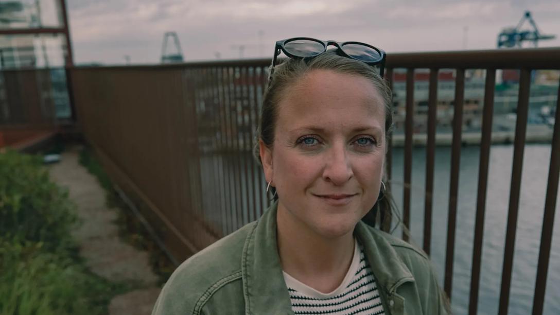 Julie kigger i kameraet med hav i baggrunden 