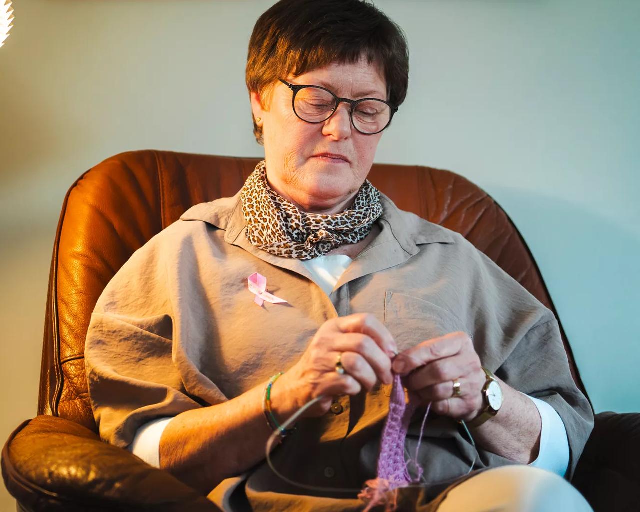Christa sidder i sofaen og strikker 