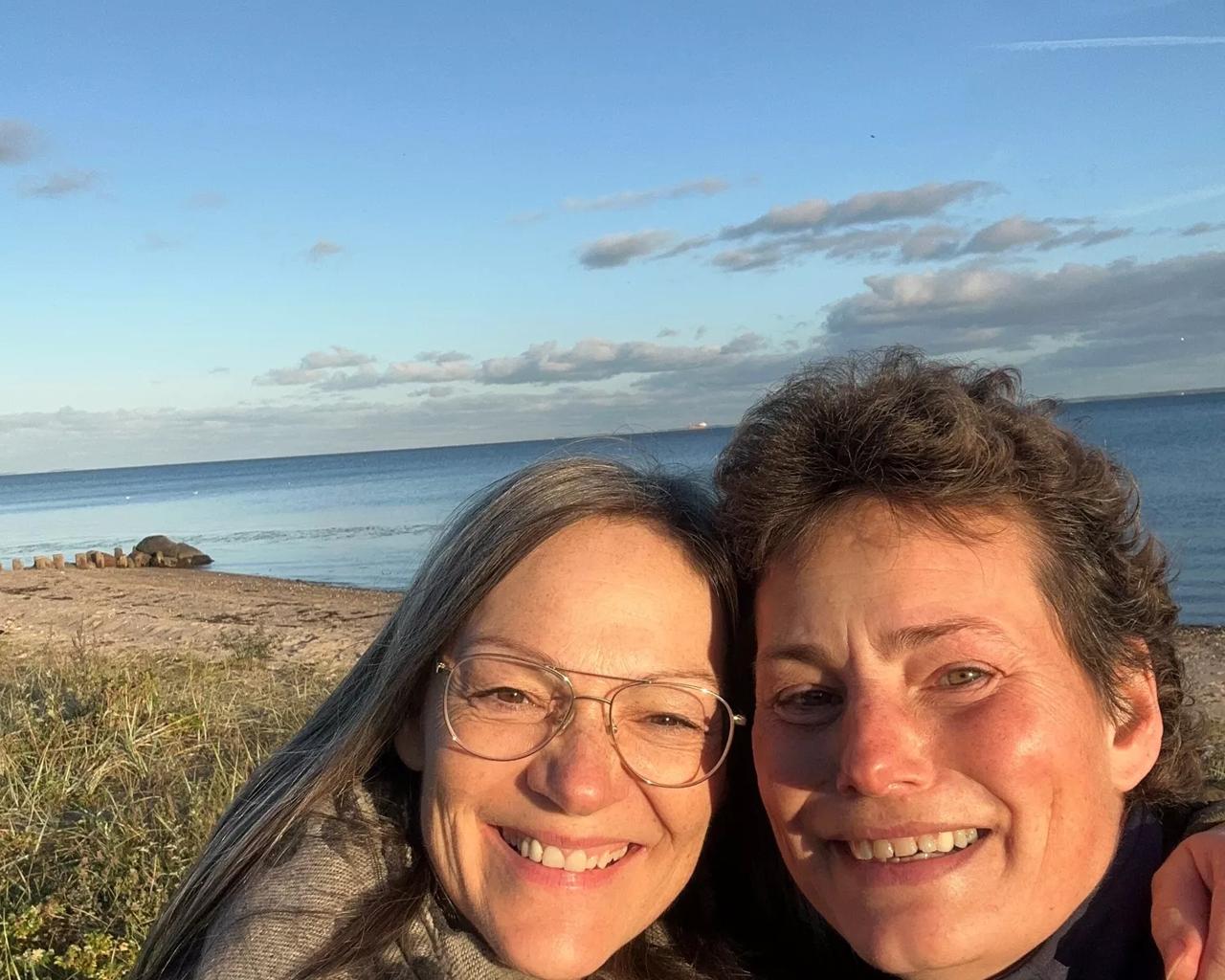 Smilende Helene og Lise på stranden i solen