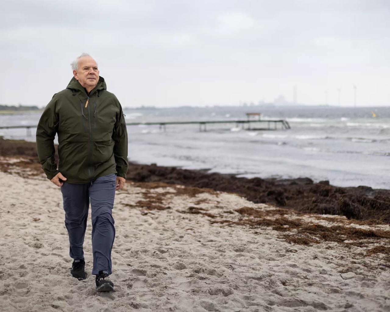 En ældre mand går i modvind ved havet