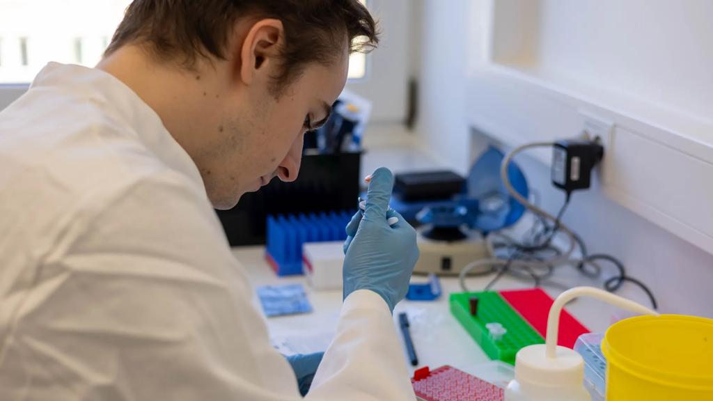 Researcher holding a pipet, performing an experiment at the bench