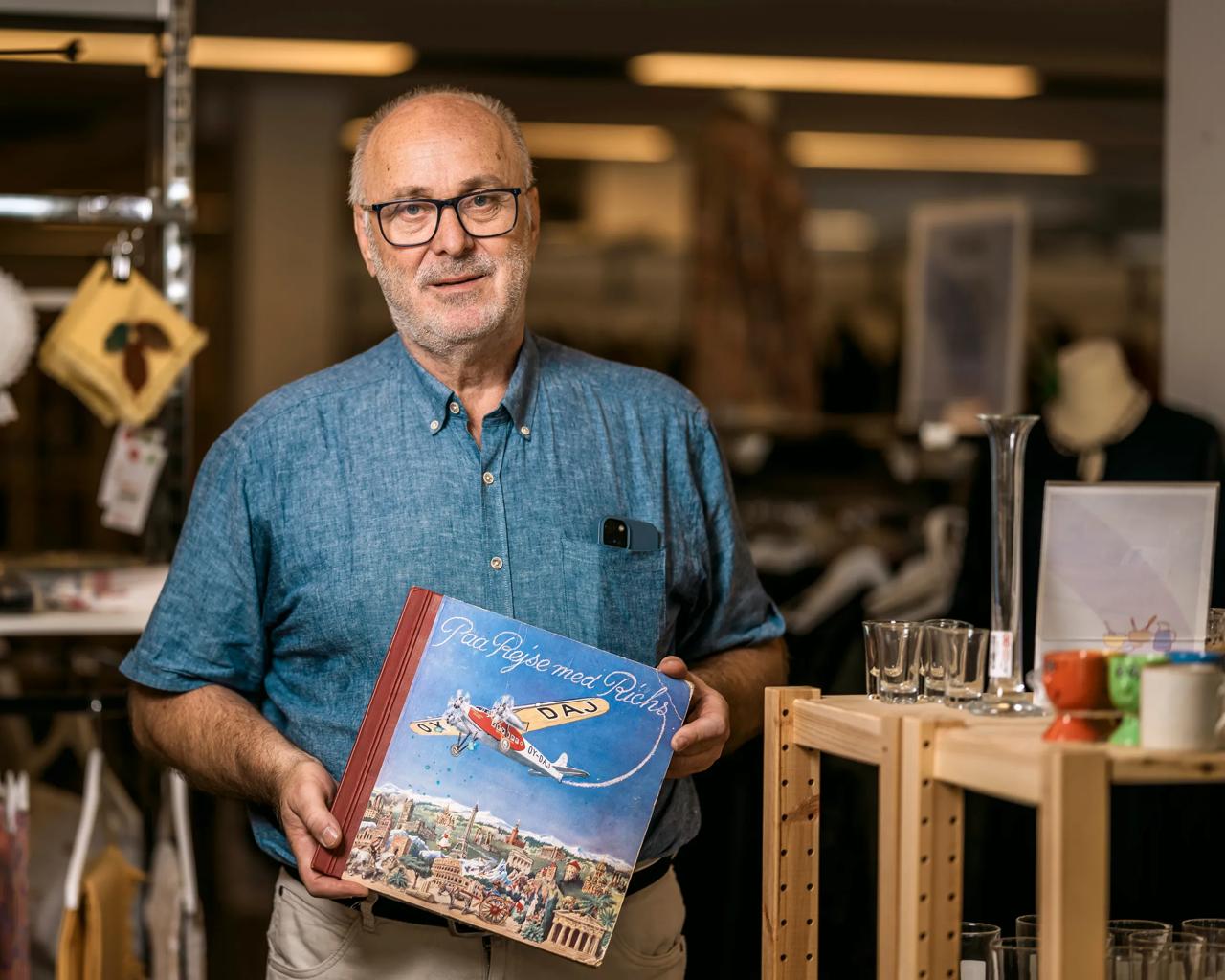 Som frivillig har Torben indført, at genbrugsbutikken også sælger genbrug online - f.eks. via Den Blå Avis. Han synes, at den næsten 100 år gamle samlebog, som han står og holder, siger nest in ham som person og frivillig.