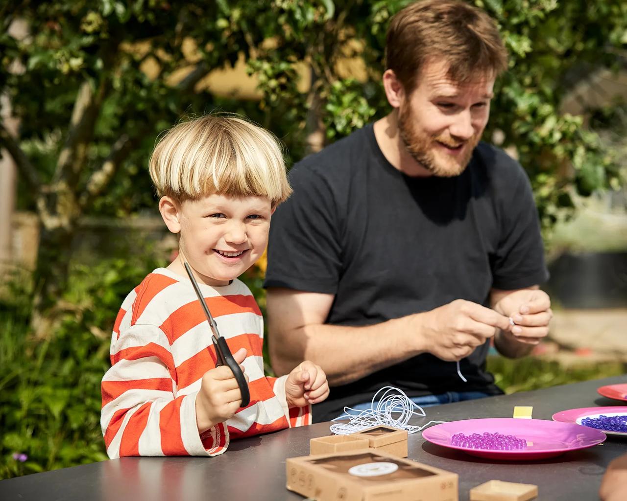 Børn laver perler med en frivillig til den lokale soluge