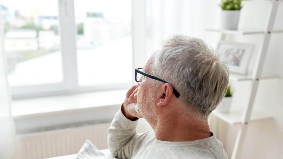 mand kigger ud ad vinduet