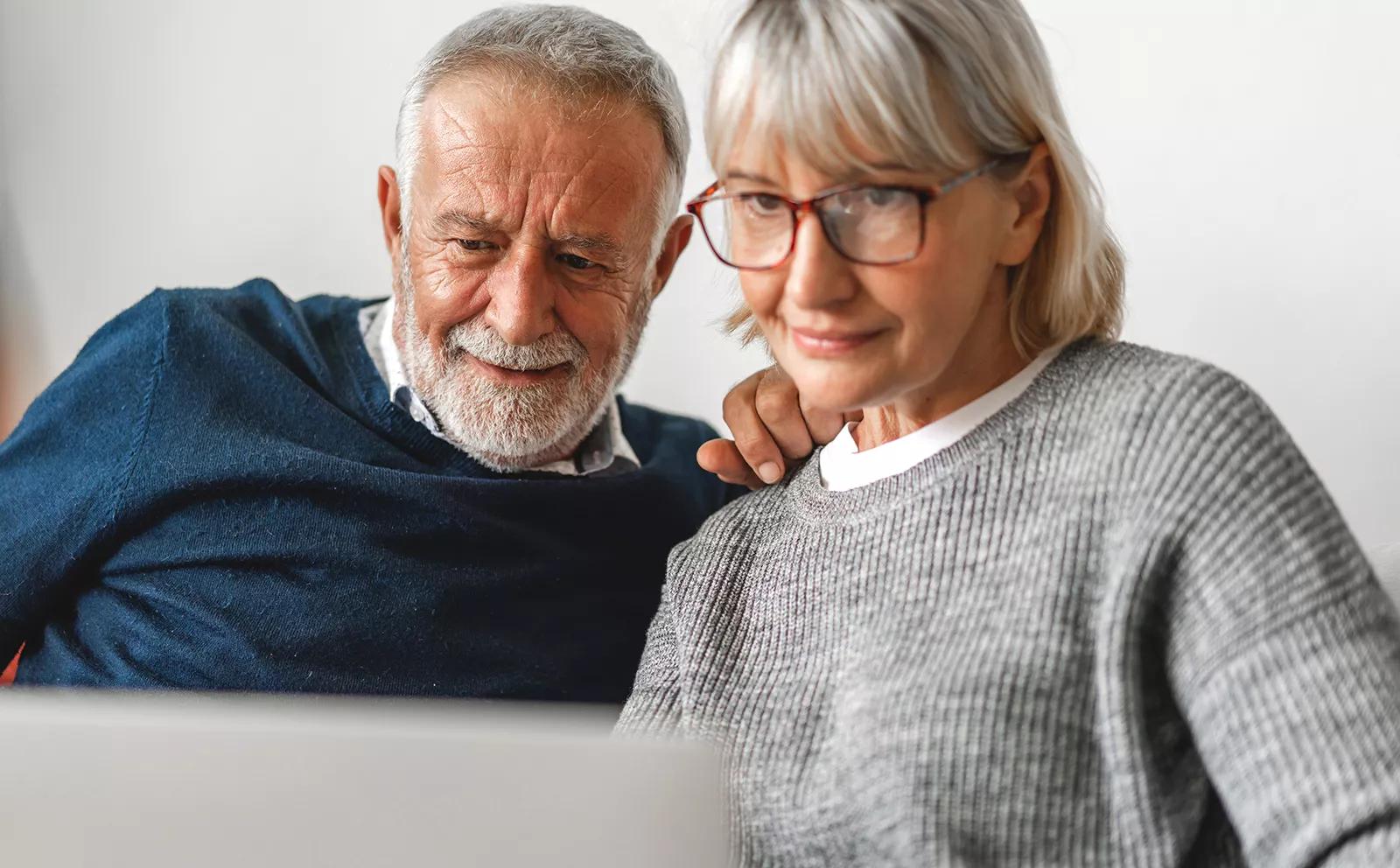 Ældre kvinde og mand ser fornøjet på computerskærn