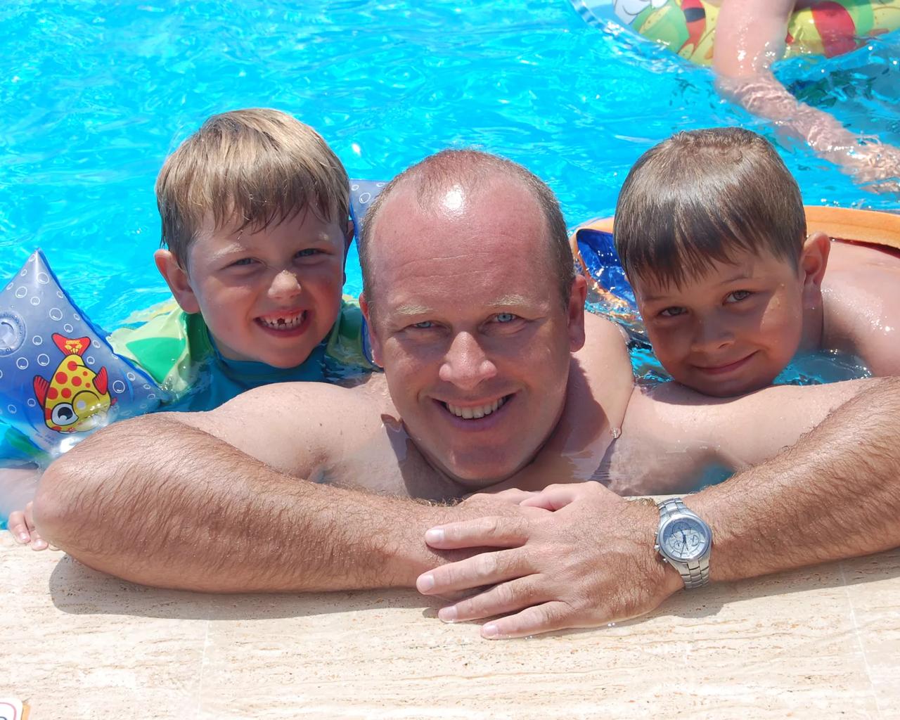 Magne og Asger svømmer rundt med deres far i en pool 
