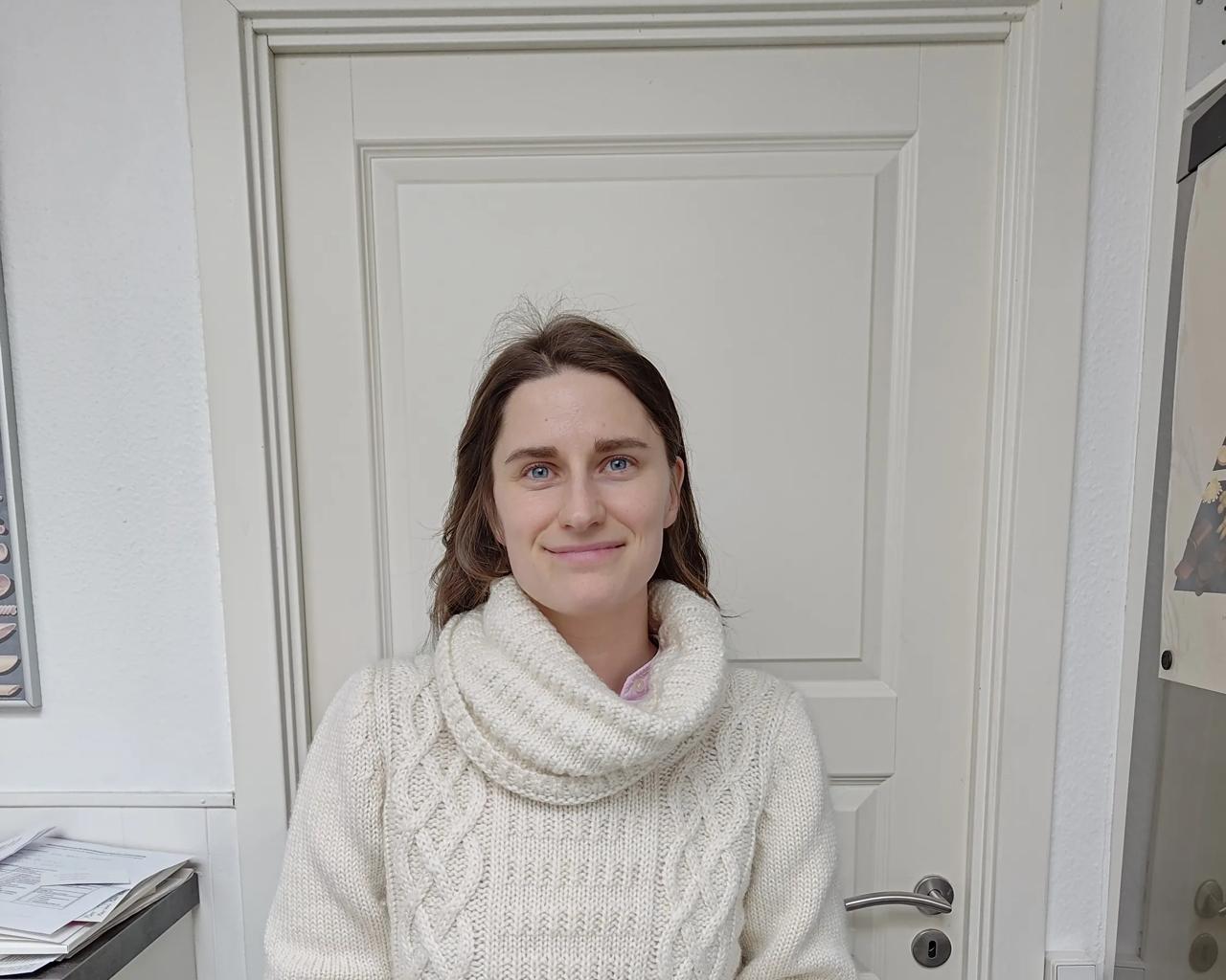 Lisa står og kigger smilende i kameraet med langt hår. 