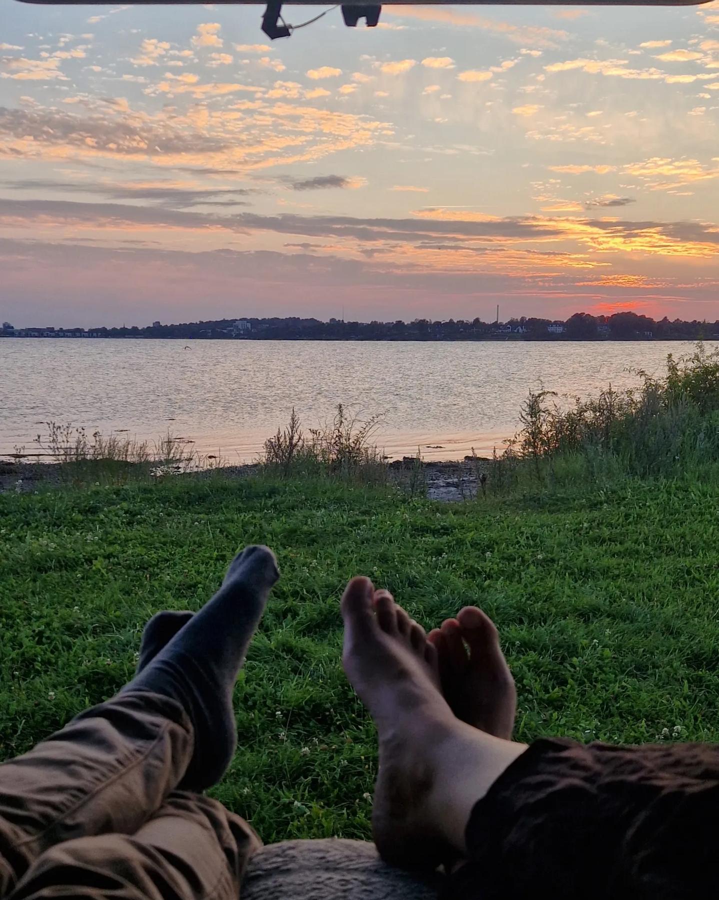 Billede set inde fra en bil omdannet til en campervan med udsigt til solnedgang. 