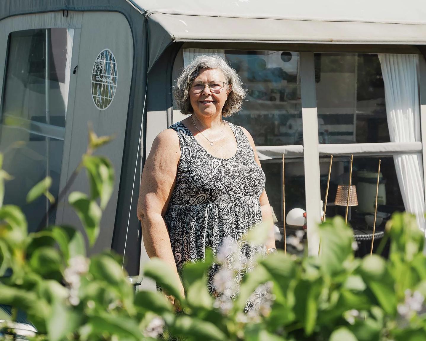 Lene står uden foran sin campingvogn i solen