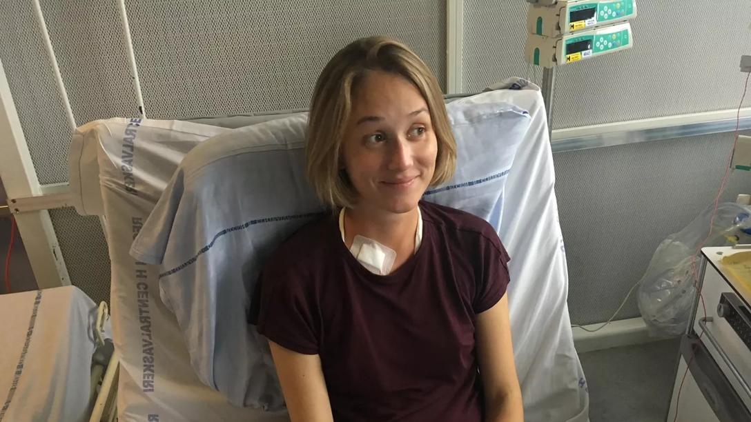 Sarah sidder i en hospitalsseng