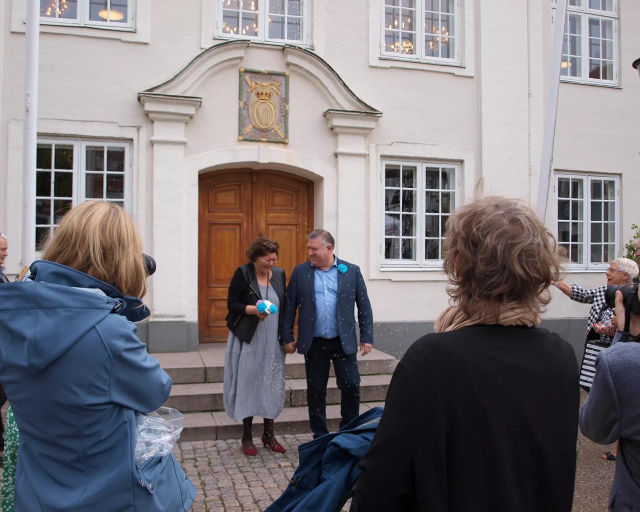 Kristine og Thomas står foran rådhuset, mens der kastes ris på dem.