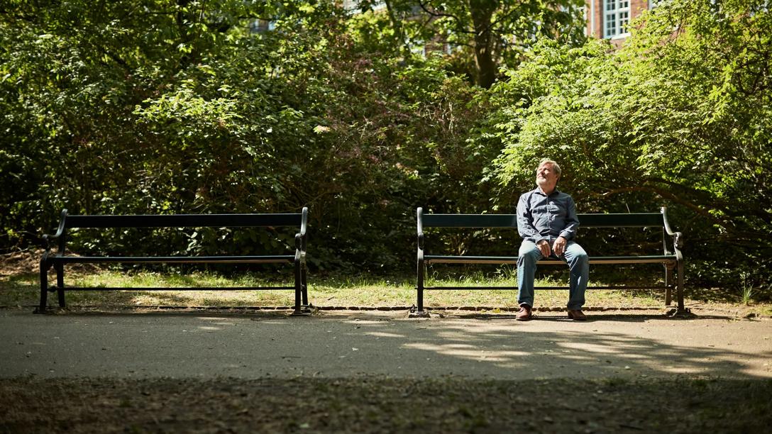 Mand der sidder på en bænk i naturen