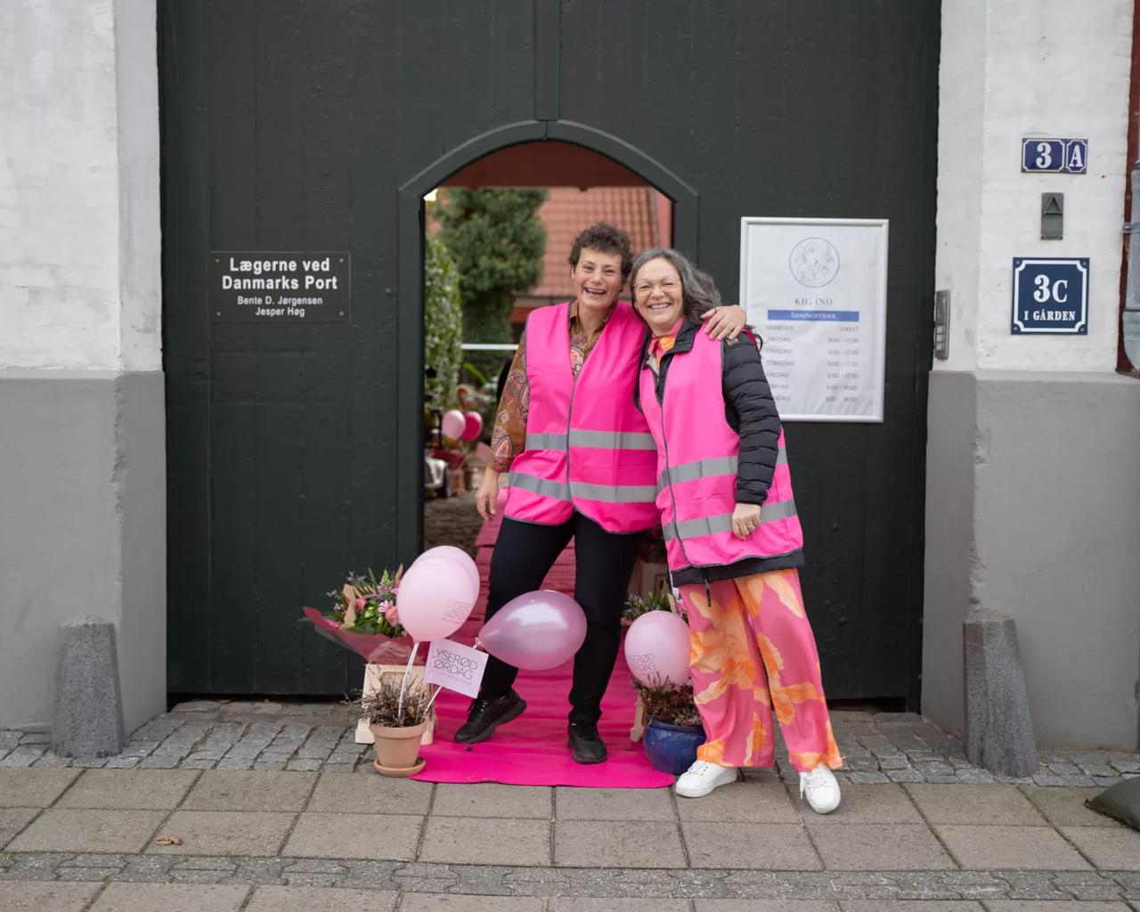 Helene og Lise iført lyserøde veste foran cafeen 