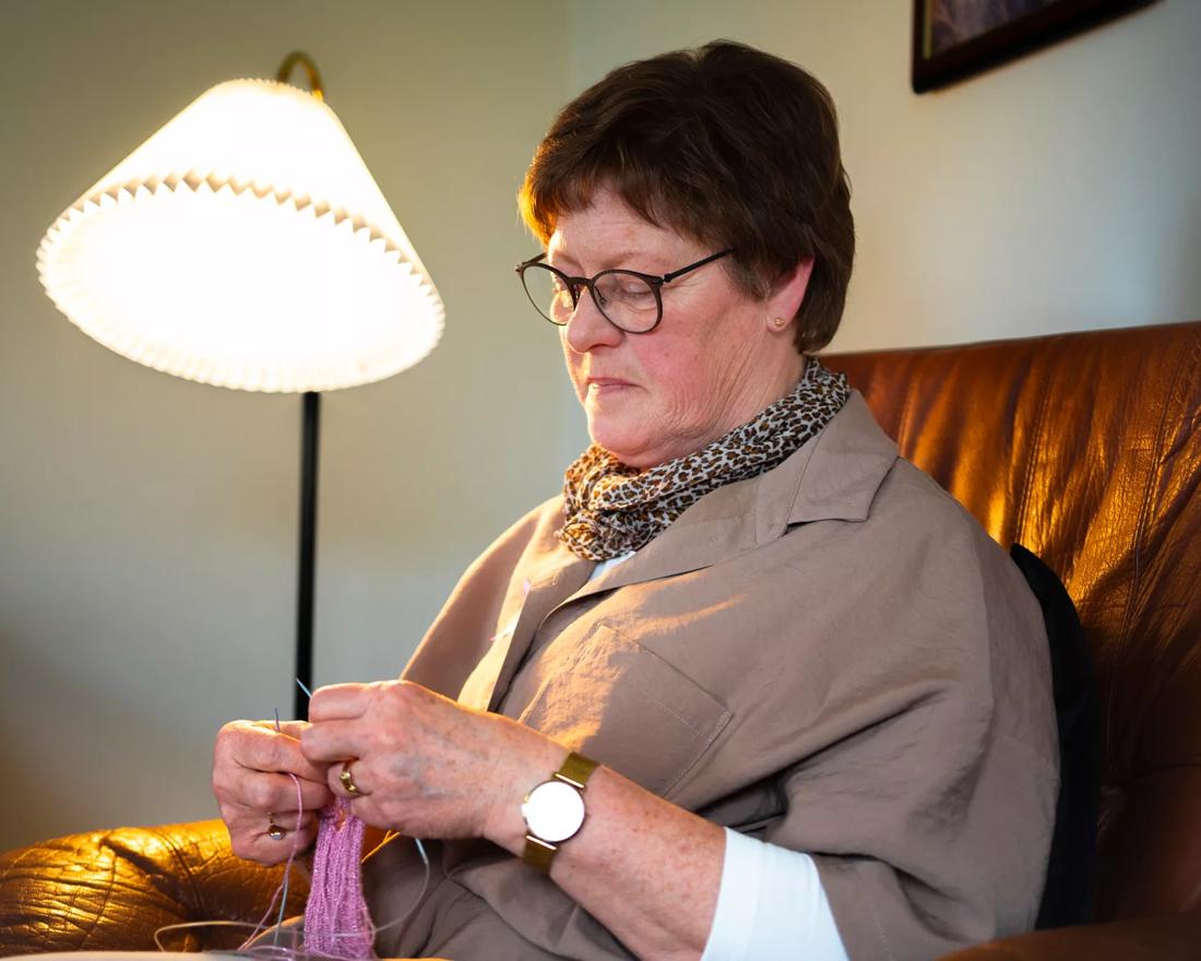 Christa sidder i sofaen og strikker 