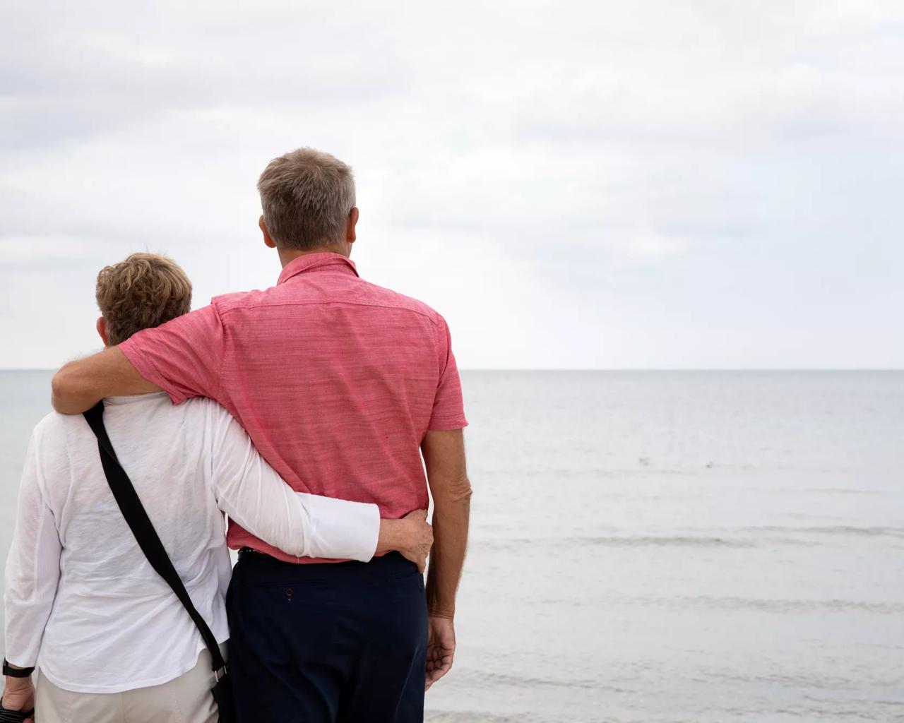 En mand og en kvinde holder om hinanden og kigger ud over havet