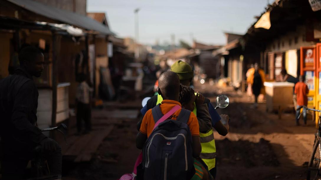 En mand og hans to sønner sidder på en knallert og kører igennem Kampala, Uganda 