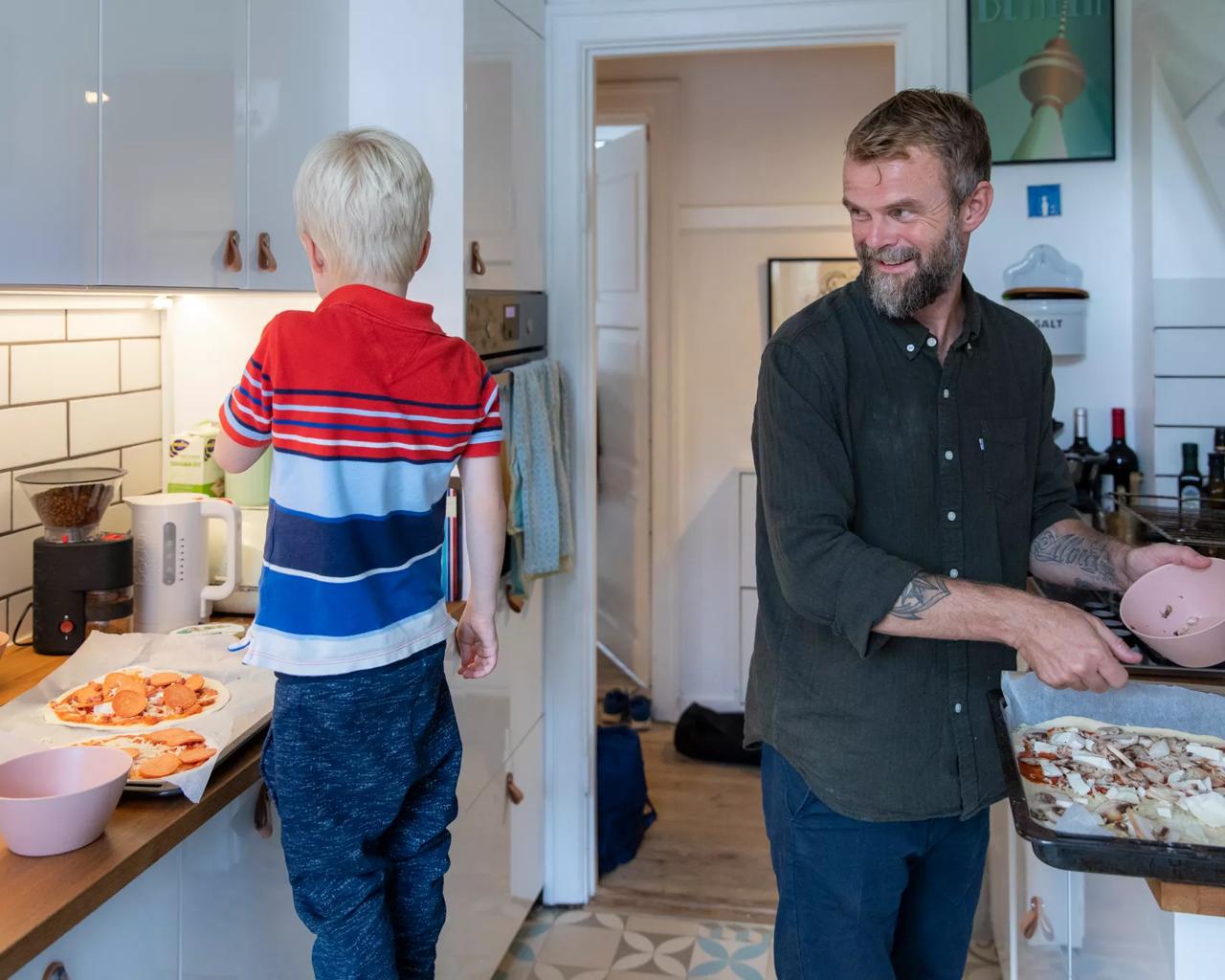 Smilende mand laver pizza sammen med sin søn