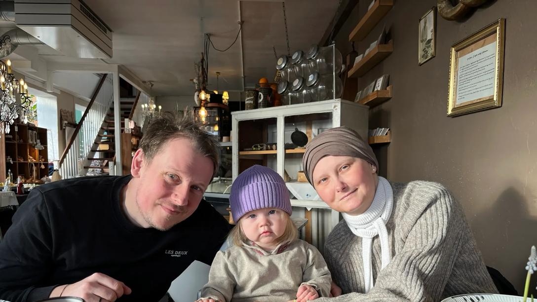 Brian, Freja og Julie sidder sammen på café og kigger smilende i kameraet. 