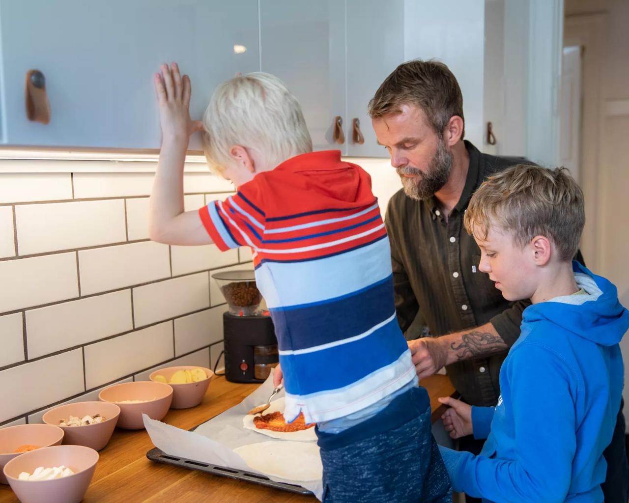 far og to børn laver mad sammen i et køkken