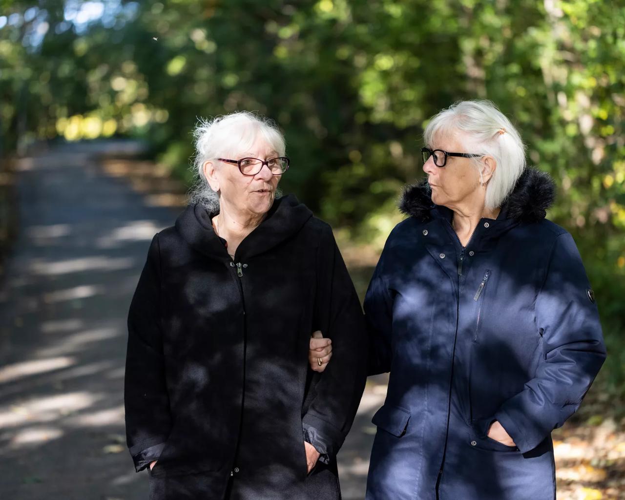 To ældre kvinder går tur sammen i efterårssol